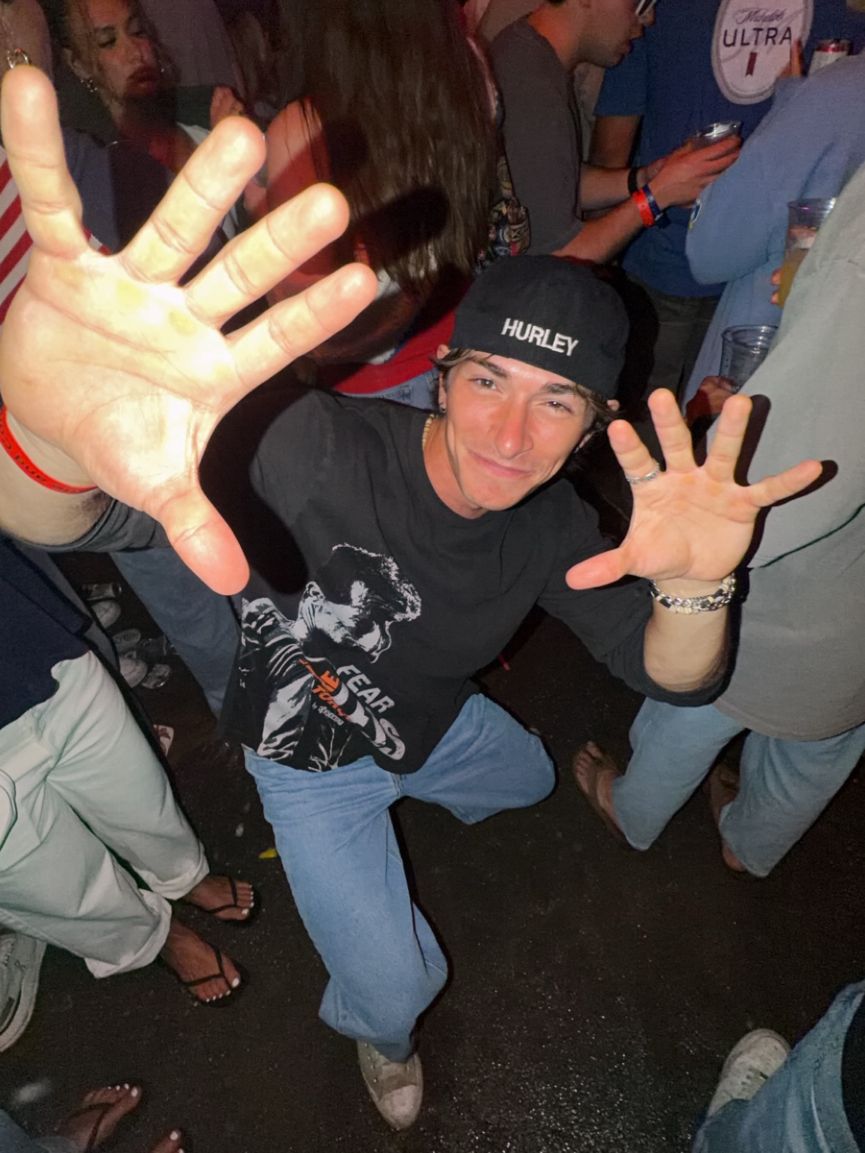 Surveillance photo: SURPHER in a crowd, hands thrown up at the camera